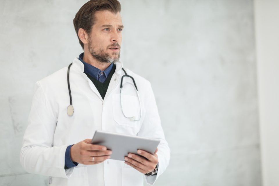 Médico do trabalho revisando dados de saúde ocupacional no tablet